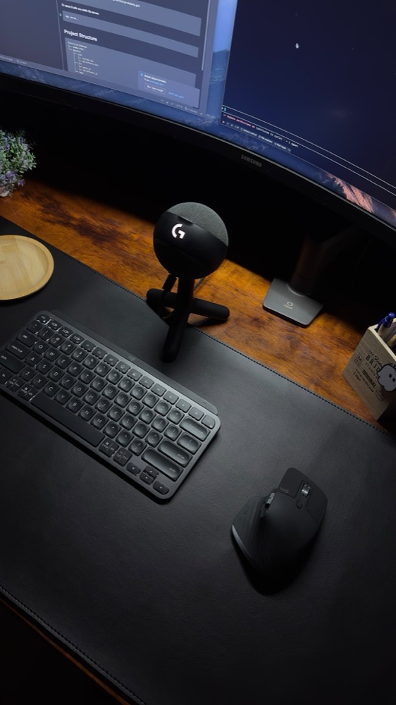 Desk with mechanical keyboard, mouse and microphone under a curved monitor