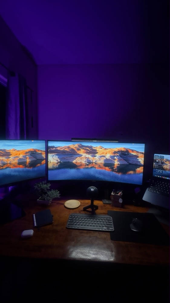 Purple-lit desk with two monitors, keyboard and microphone