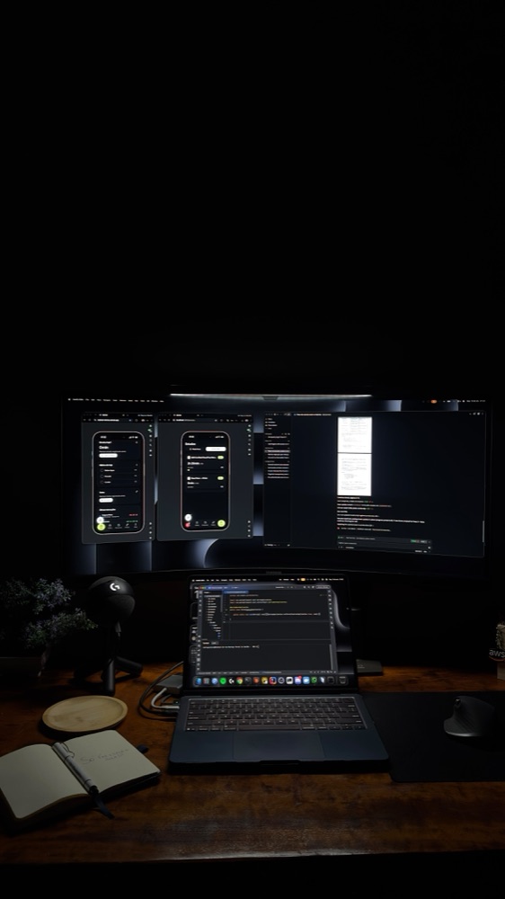 Ultrawide monitor and laptop running code, notebook on the desk