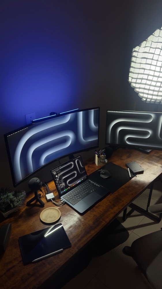 Wooden desk with curved monitor, laptop, tablet and softbox light